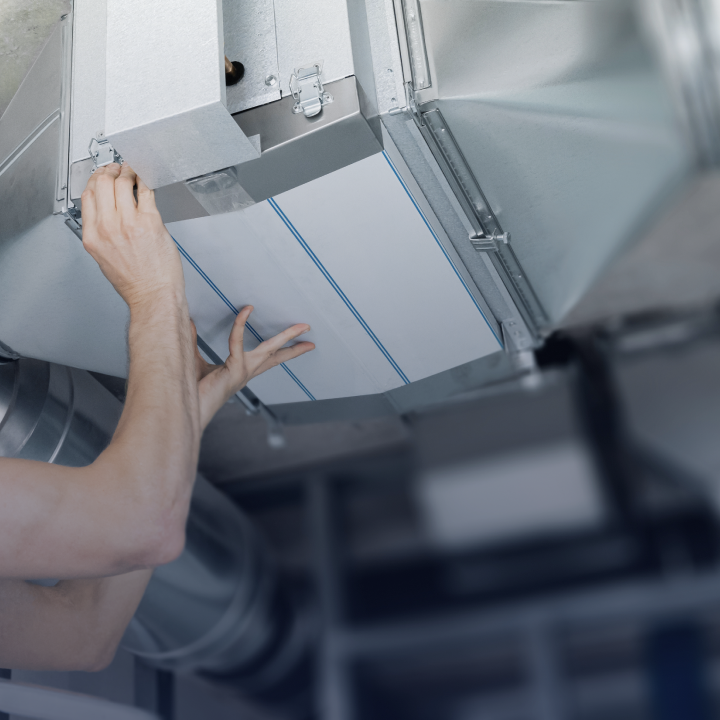 A person inspecting an HVAC system in the ceiling of a home