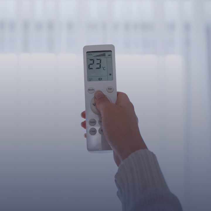A person holding a remote to control the thermostat