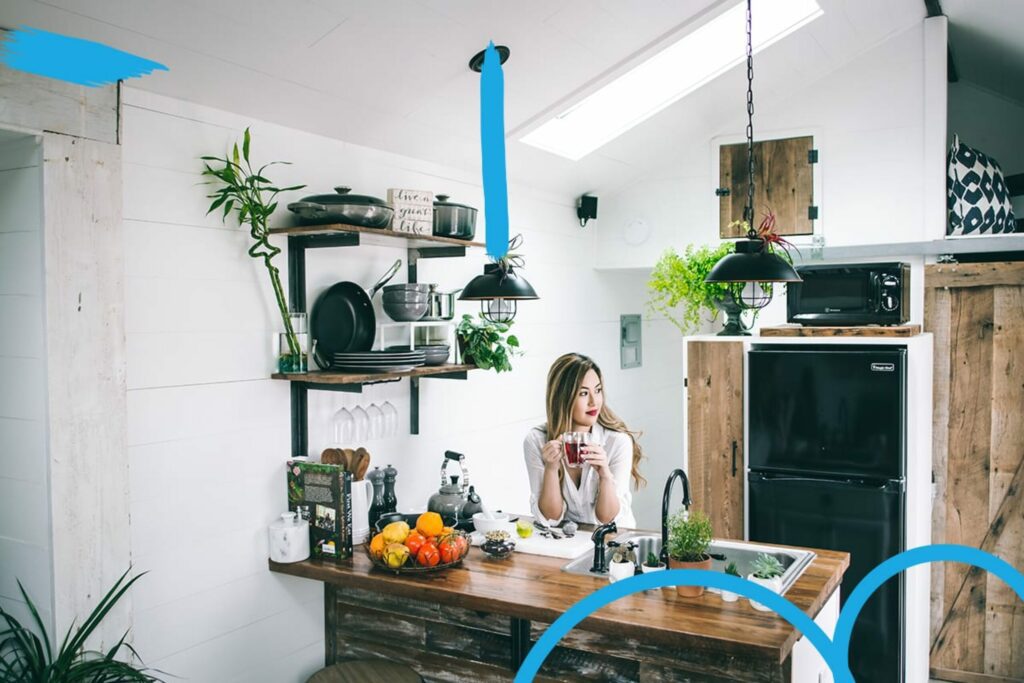 Young asian woman leaning on kitchen counter top sipping on a cup of tea