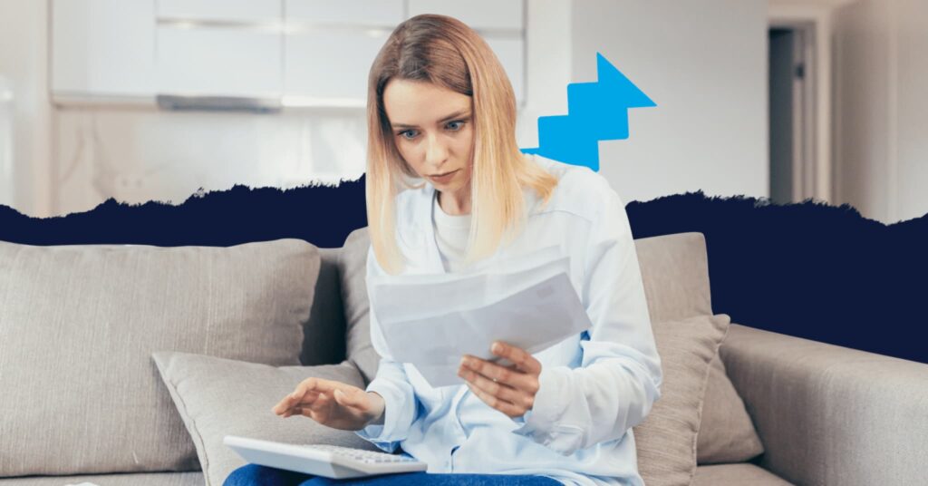 A woman with a calculator on her lap who is holding several sheets of paper and looking at them with a surprised expression.