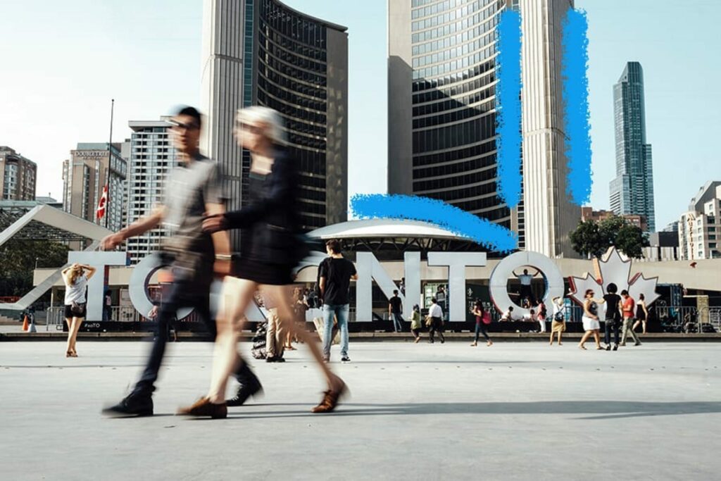 Man and woman walking by the Toronto nathan phillips square