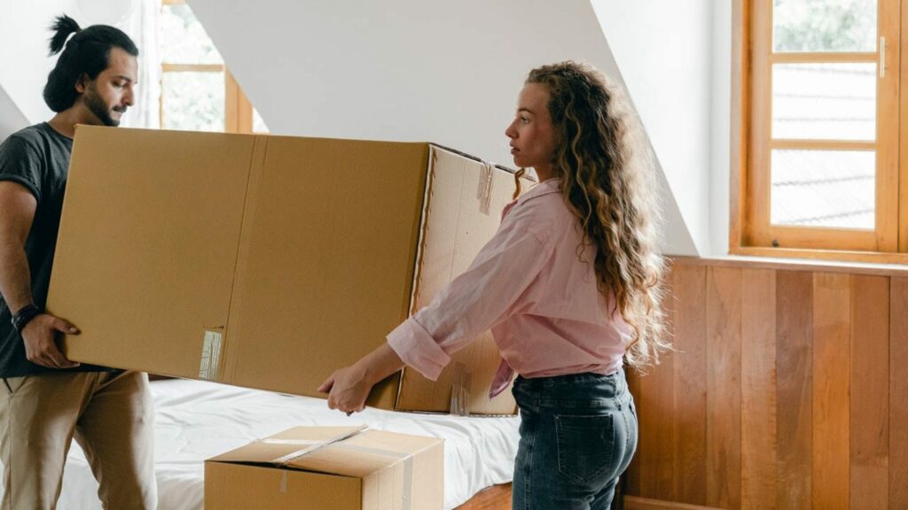 Young couple moving a large moving box together
