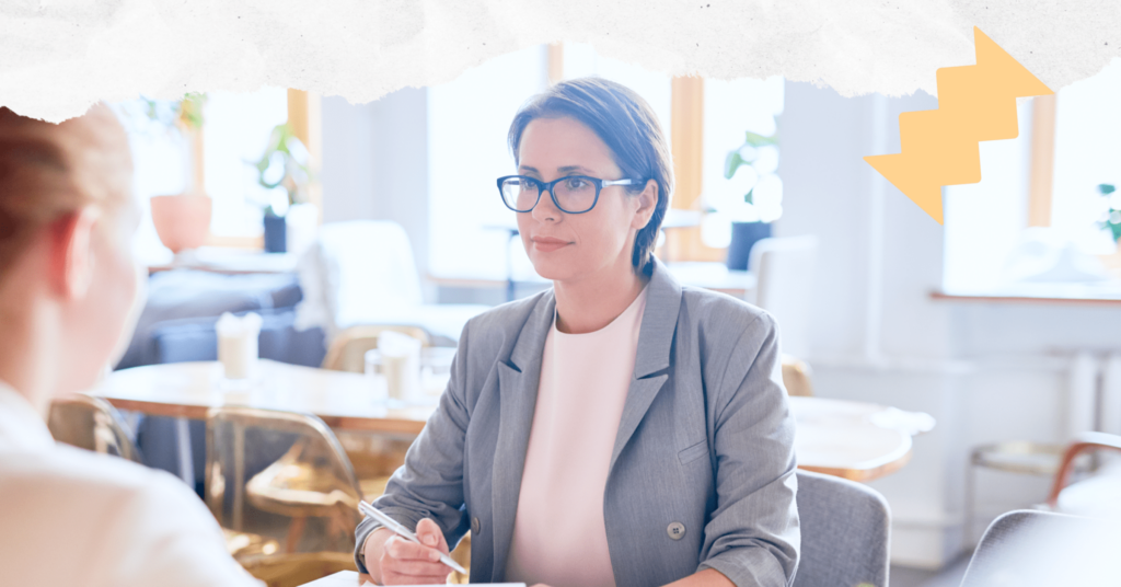 A person holding a pen and sitting across a desk from another person during a tenant screening interview.