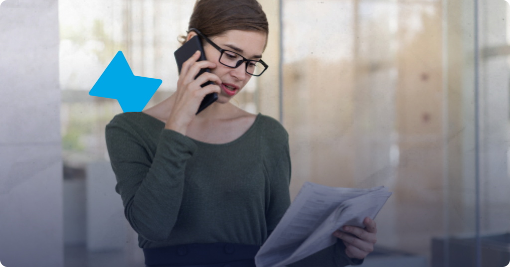 A woman is on the phone while looking at a folded stack of papers as an example of how to verify employment history