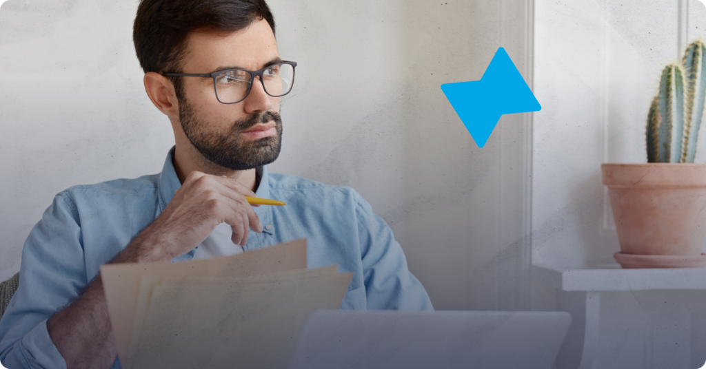 A person is sitting and holding a pencil while reviewing papers on tenant screening laws in Canada.