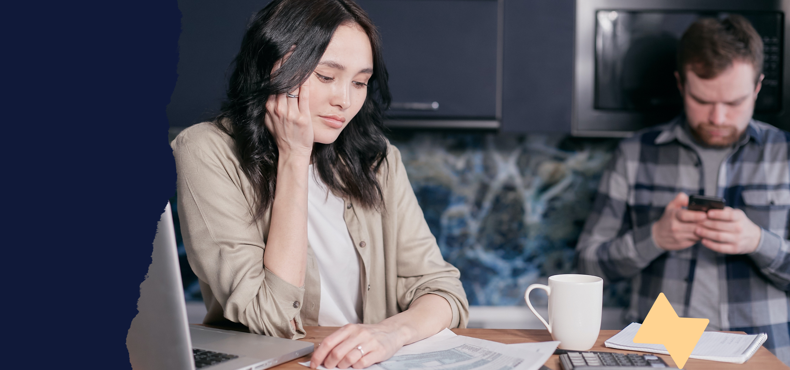 A person sitting and studying a piece of paper at their desk, resting their face against their hand.